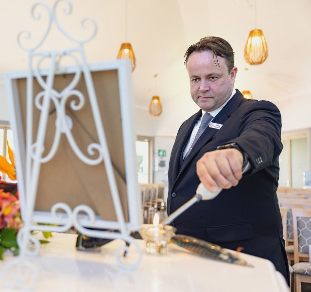 funeral director lighting candle