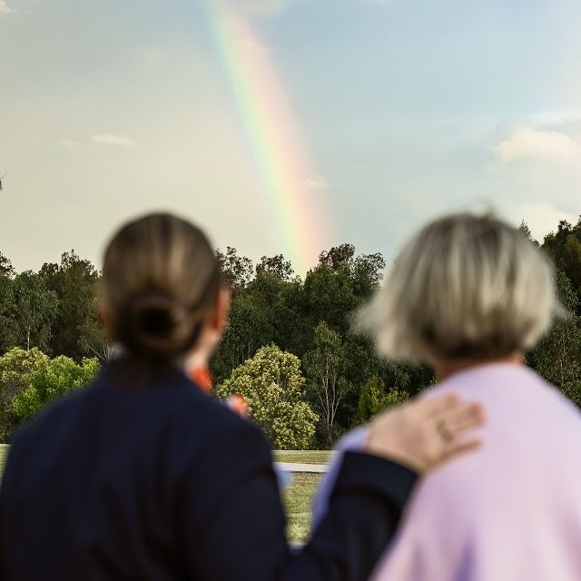 funeral director and woman looking at the rainbow